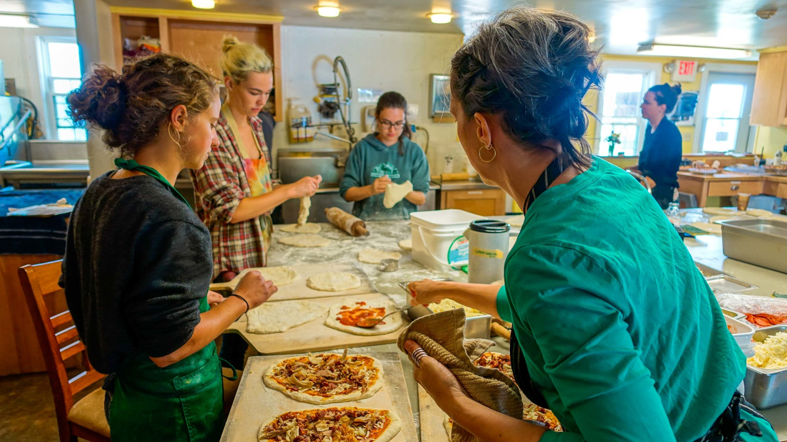 People working in the camp kitchen making pizzas.
