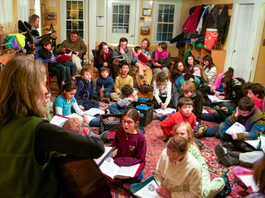 A group of campers sitting inside and singing together.