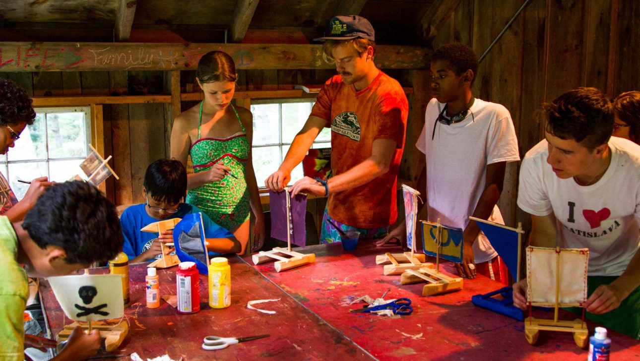 A group of campers learning how to paint their projects.