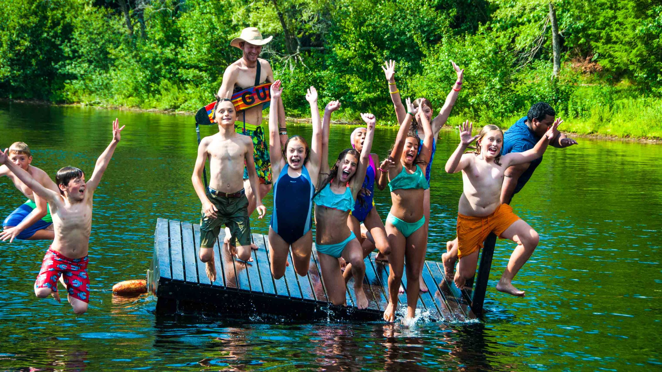 Campers jumping off a dock into the water.