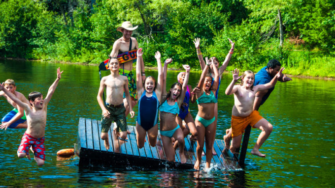 Campers jumping off a dock into the water.