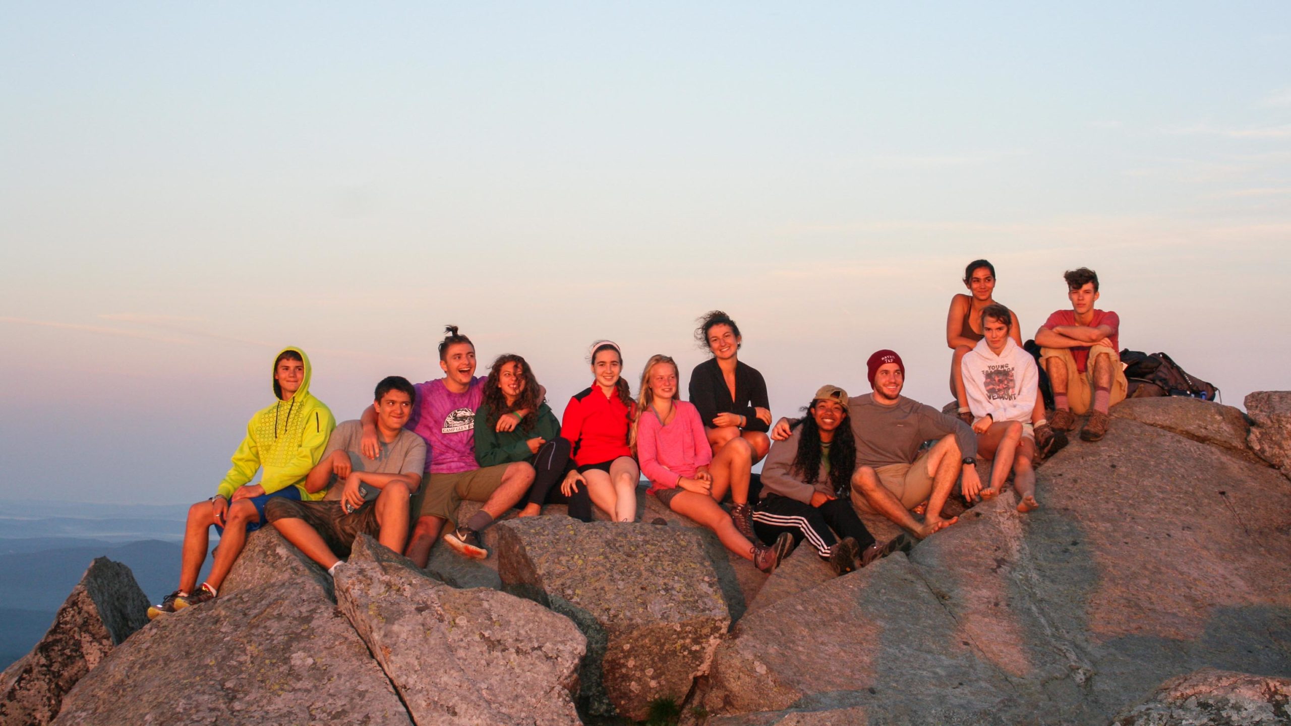 Campers sitting on a rock during sunrise.