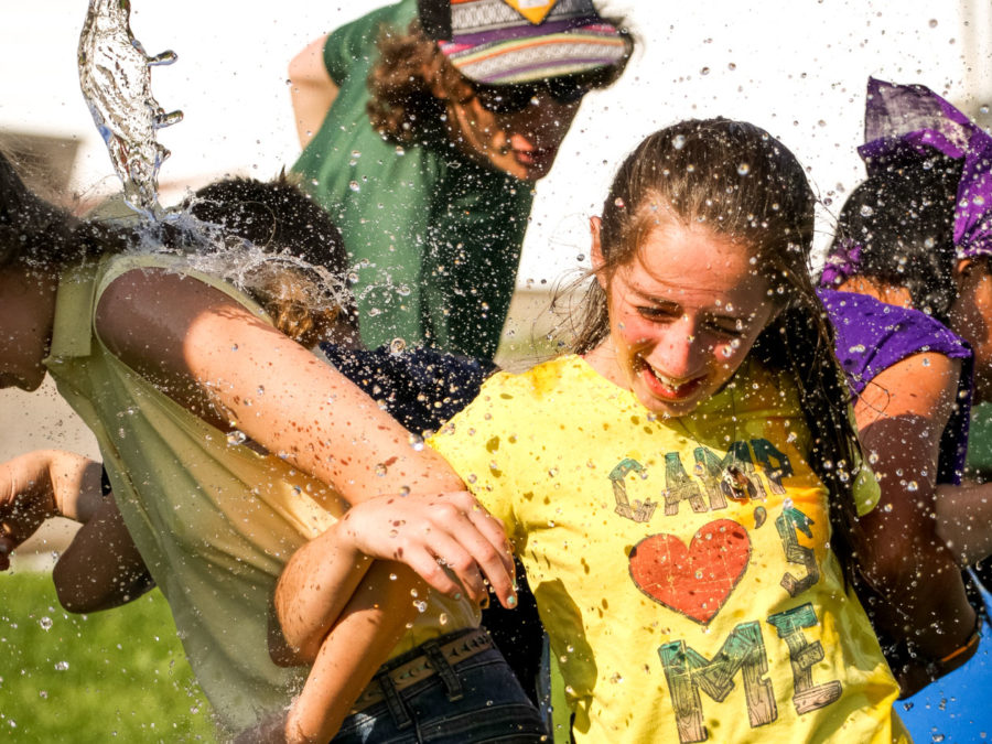 A camper getting water splashed on her while laughing.