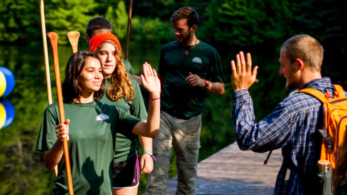 Campers high fiving each other on the dock.