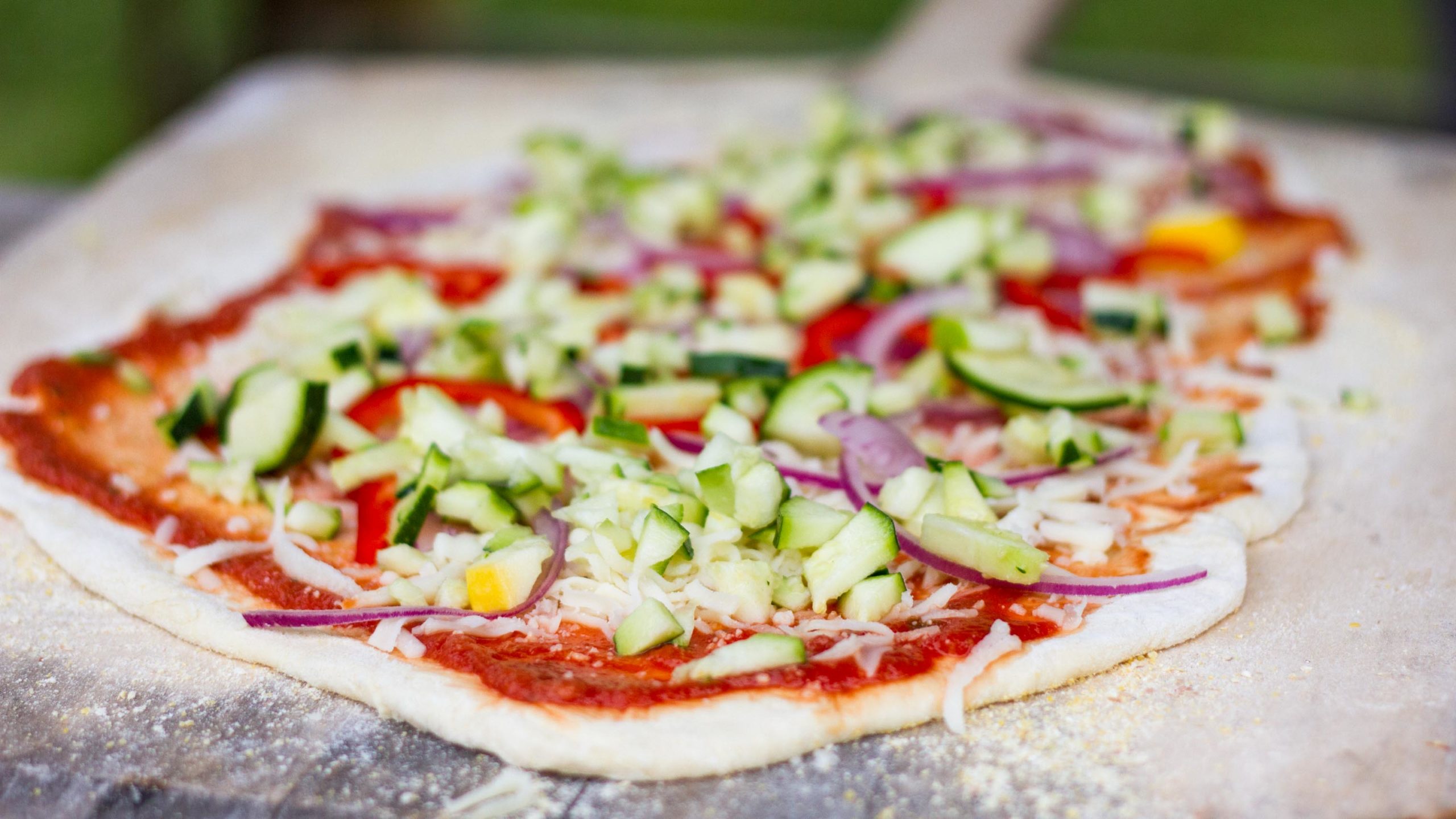 Pizza dough with toppings getting ready to be fired for dinner.