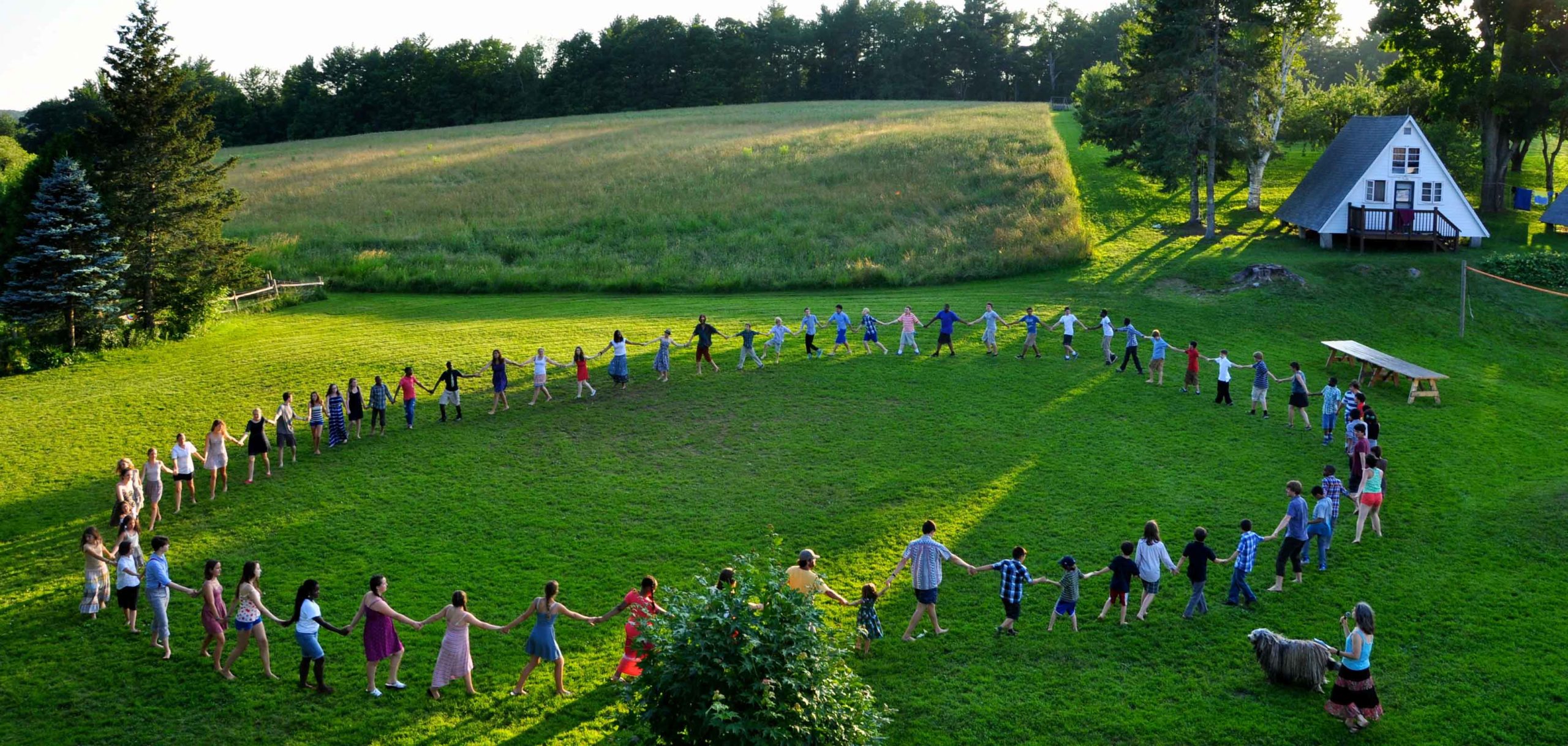 A view of people standing in a circle holding hands in a green field