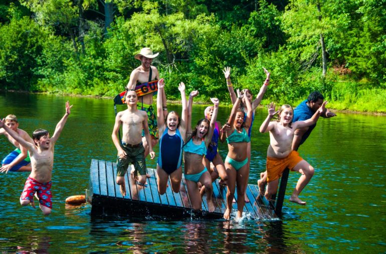 Campers jumping off a dock into the water.