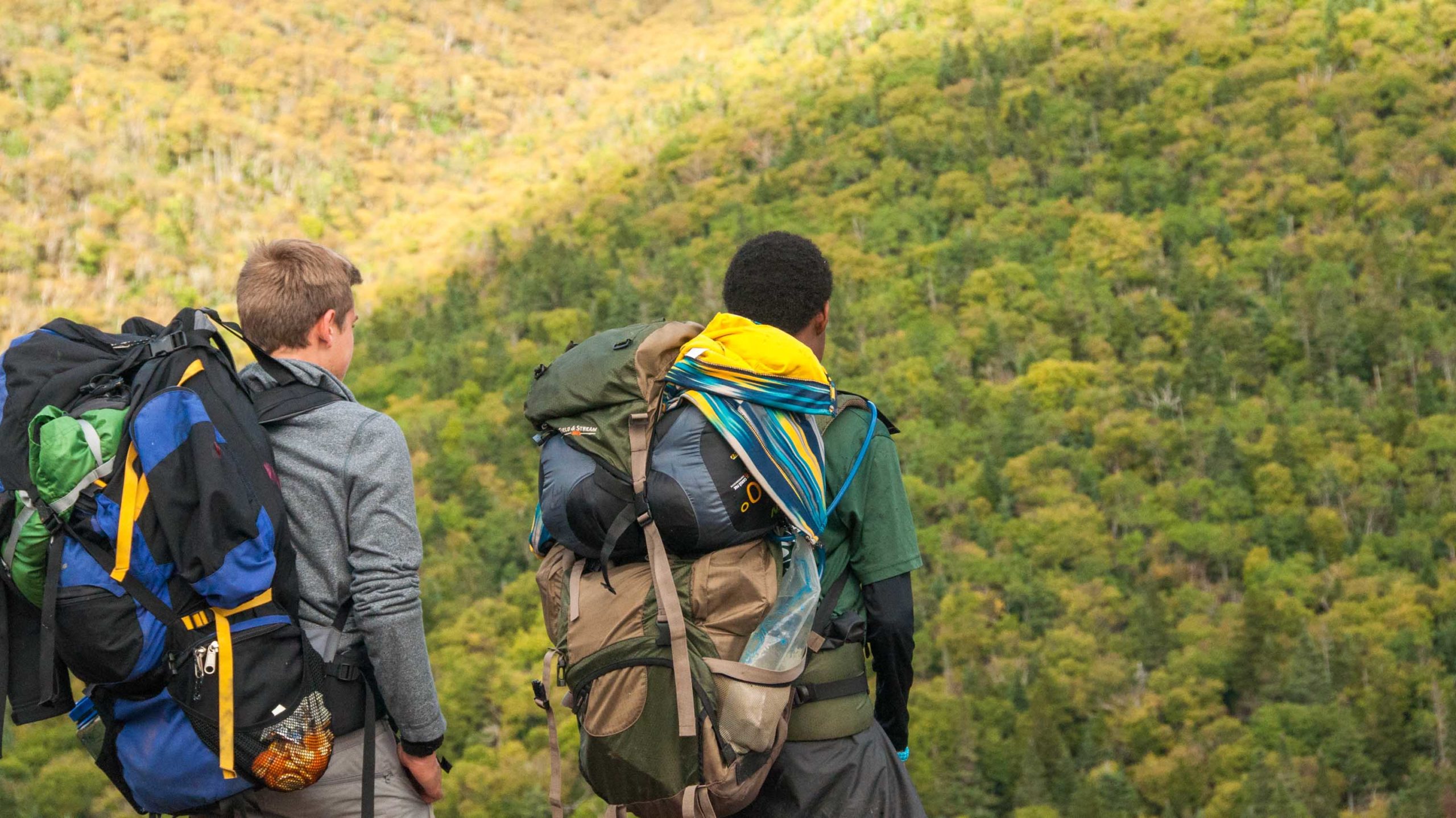 Campers hiking with packs in the mountains.