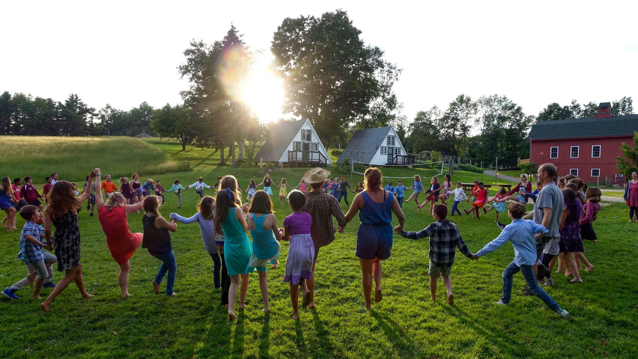 A view of people standing in a circle holding hands in a green field